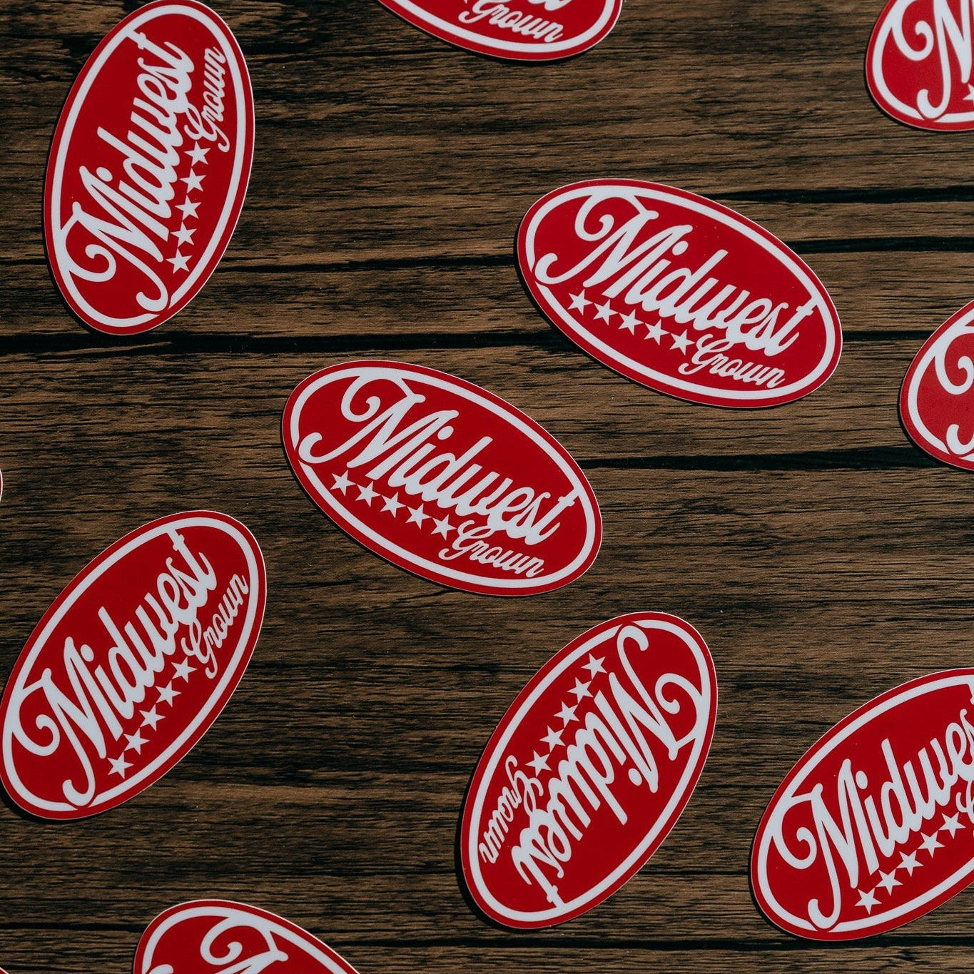 Red and white 'Midwest' logo stickers on a wooden surface
