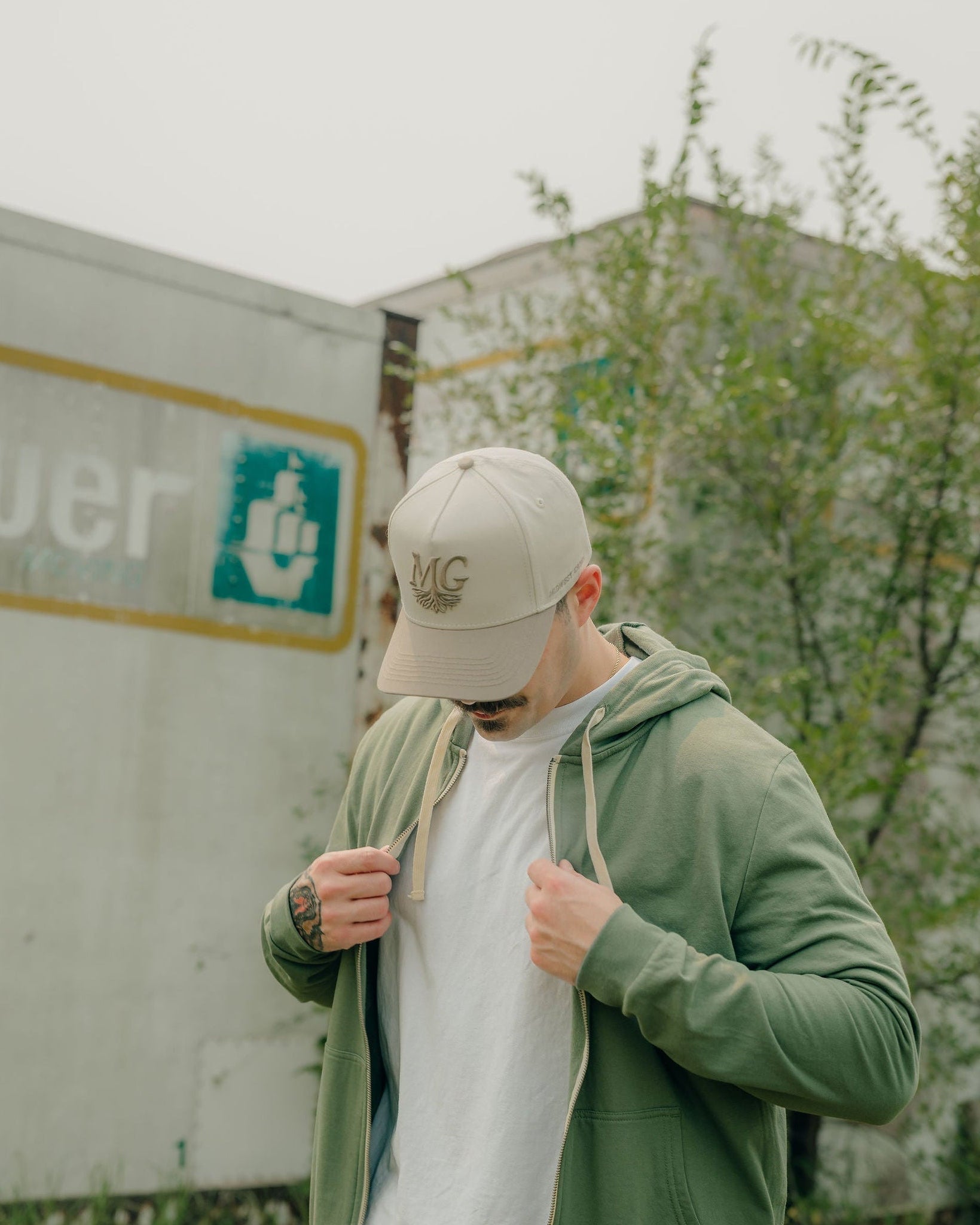 Man wearing a green hoodie and beige Midwest Grown cap in front of a truck with a visible brand logo.