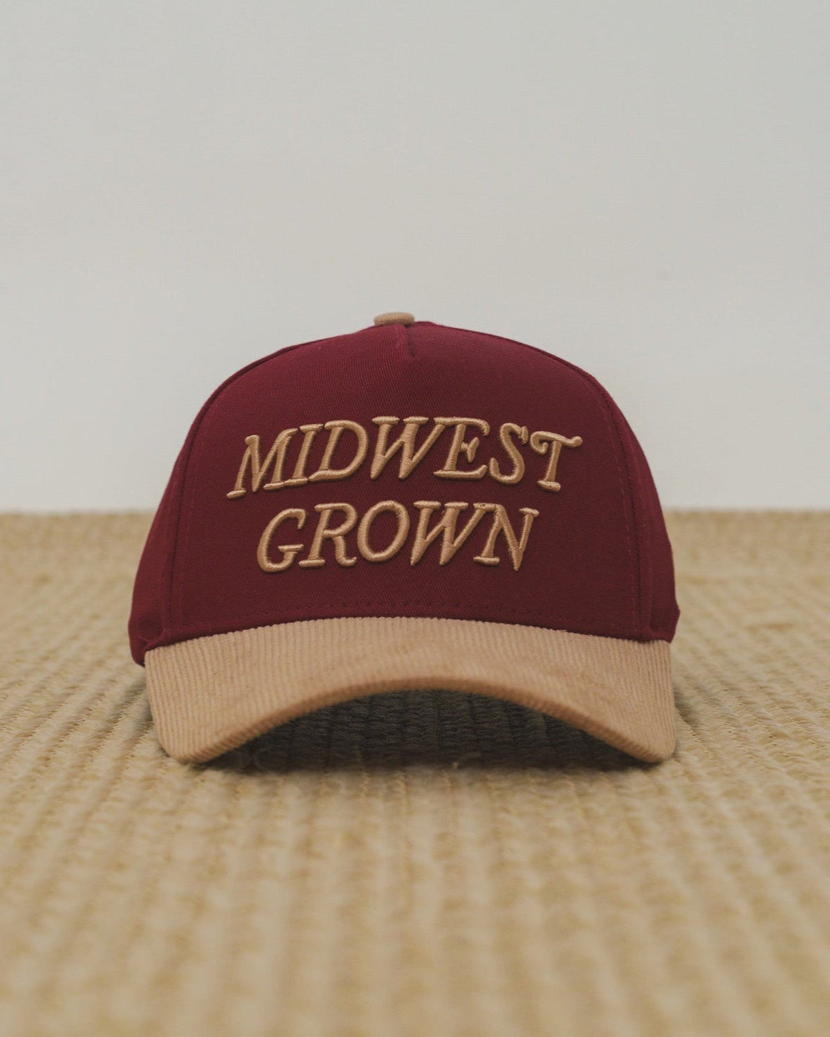 Maroon and beige cap with 'Midwest Grown' text on a textured surface.