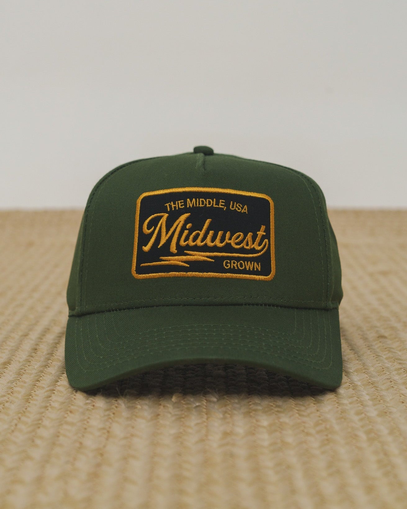 Green cap with 'Midwest Grown' logo on a textured surface