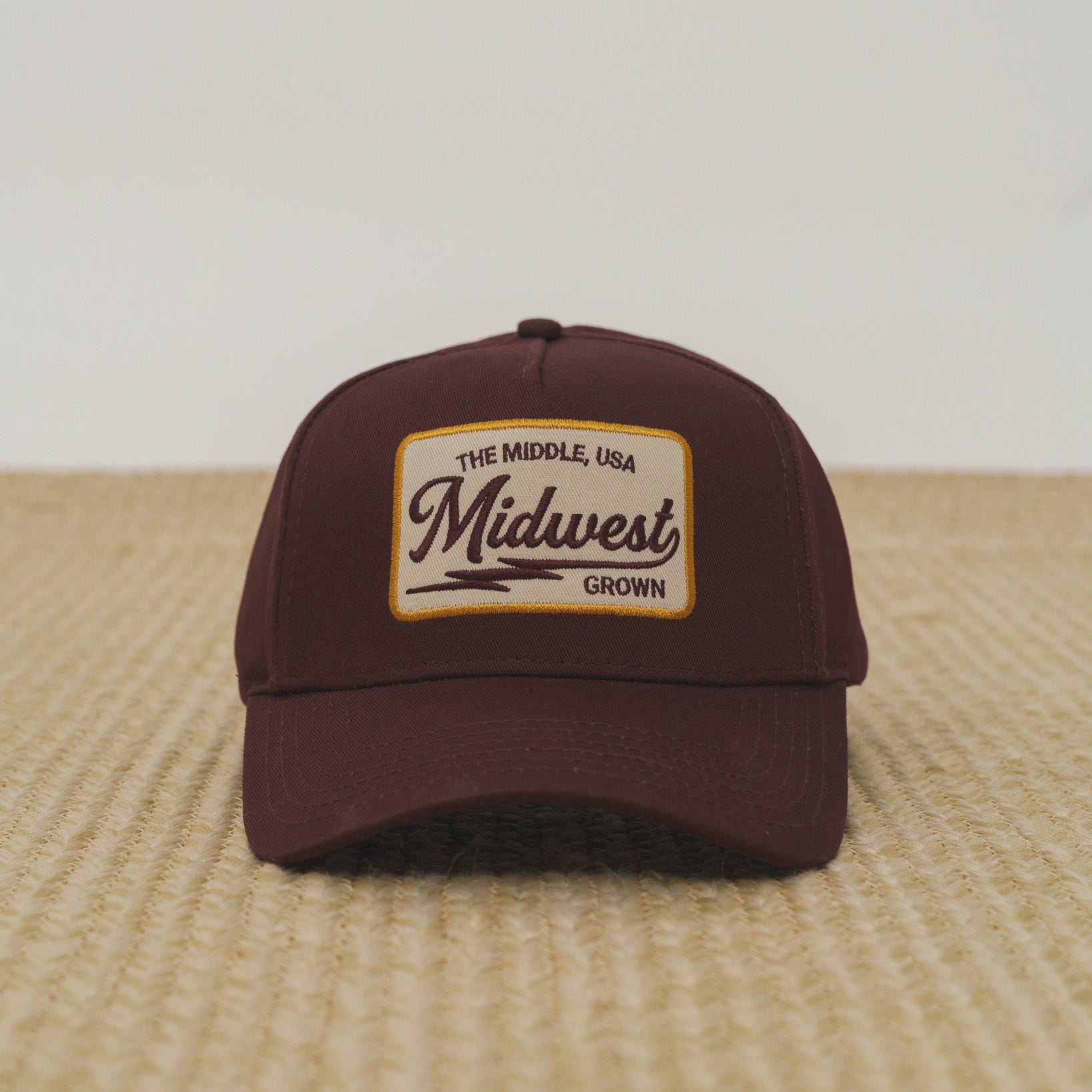 Brown cap with 'Midwest Grown' logo on a textured surface