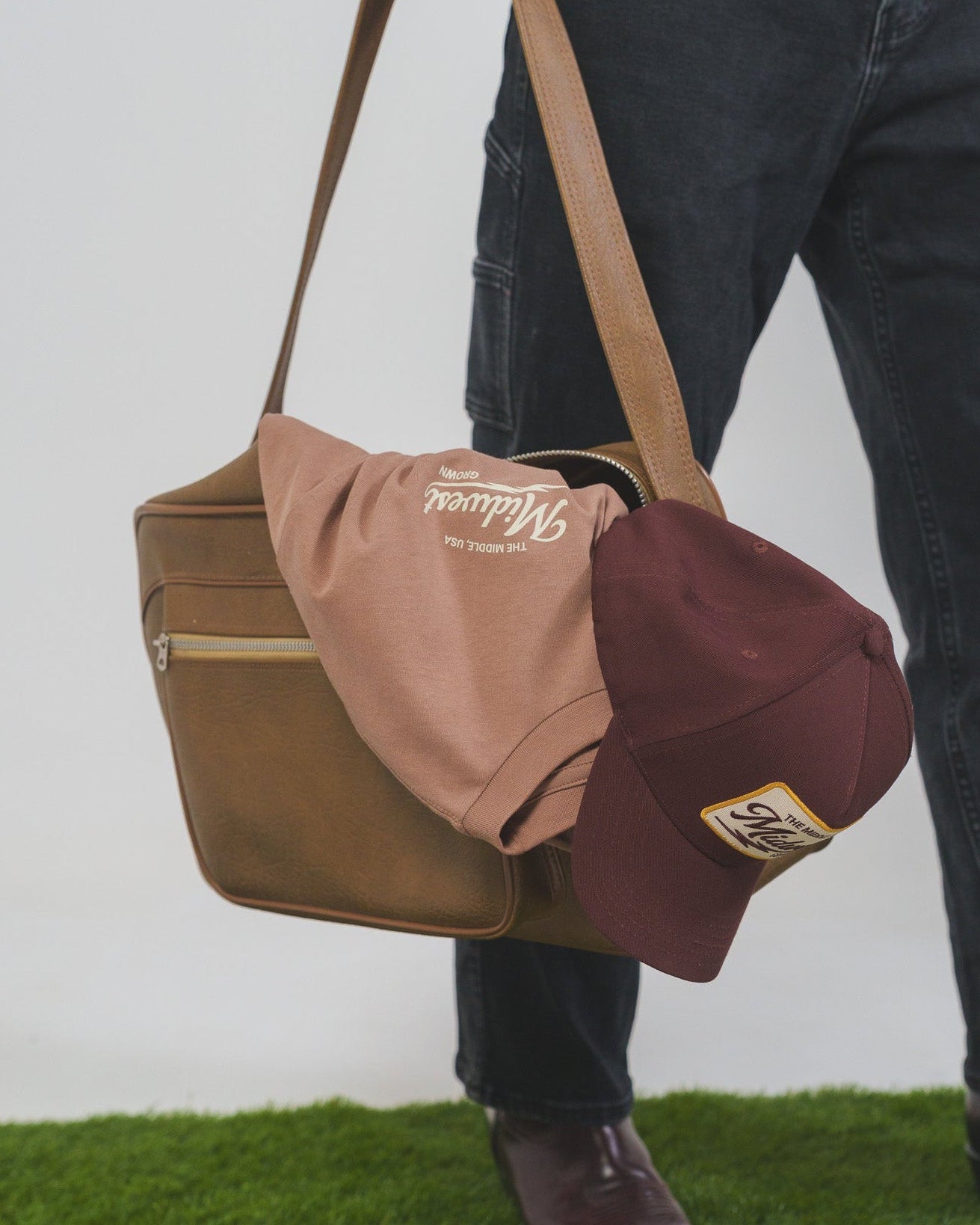 Person holding a brown bag with a Midwest Grown Shirt and Hat