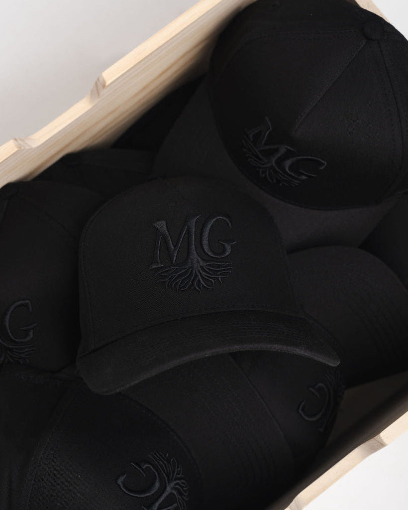 Black caps with a Midwest Grown logo in a box on a light gray background