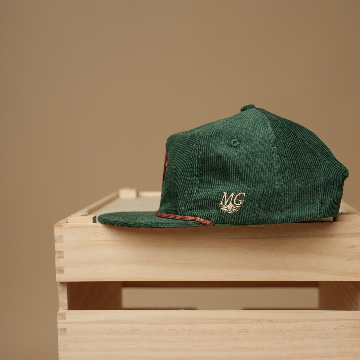 Green cap with a Midwest Grown logo on a wooden crate against a beige background