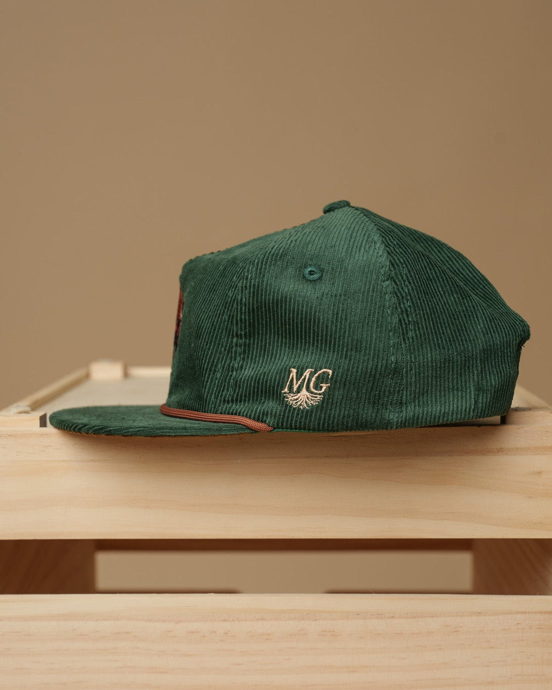 Green cap with a Midwest Grown logo on a wooden crate against a beige background