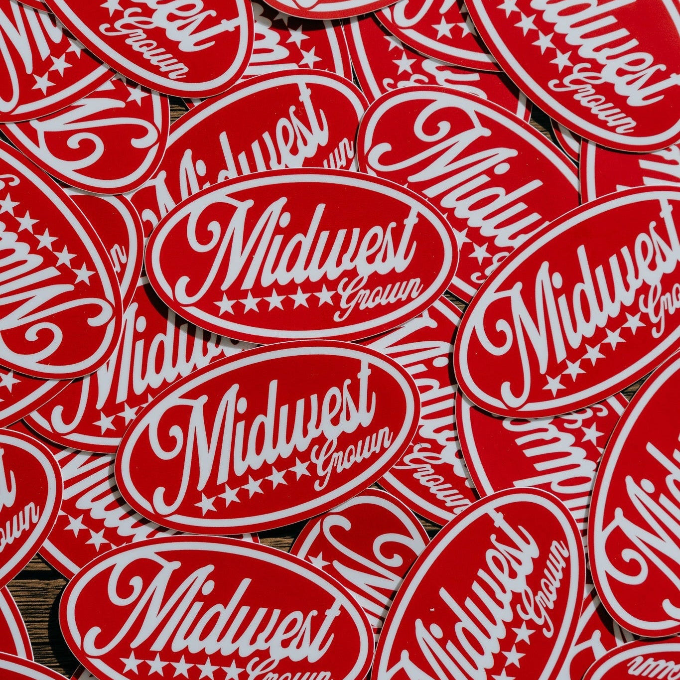 Stack of red and white stickers with 'Midwest Grown' text on a wooden surface.