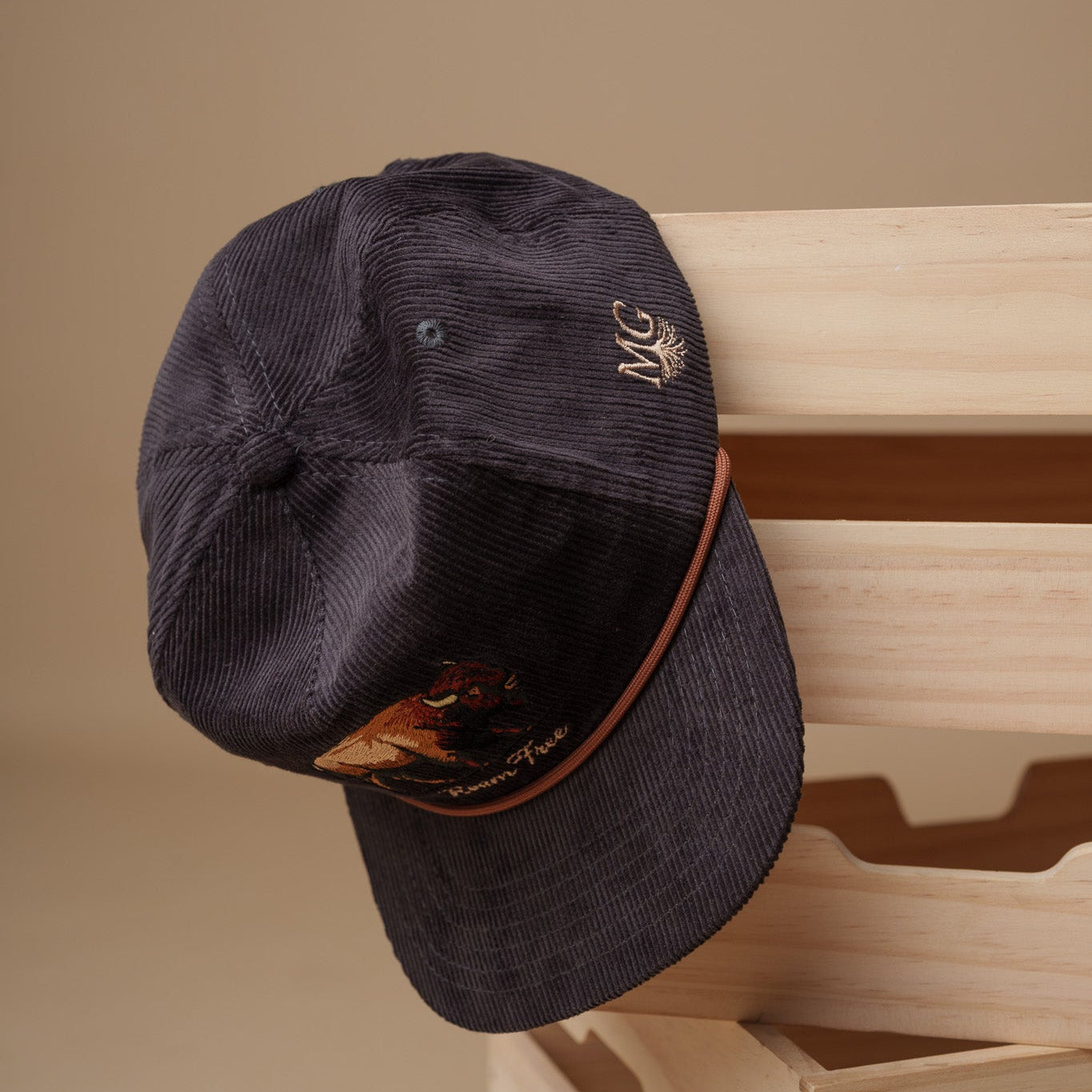 Vintage Gray cap with a Midwest Grown logo on a wooden surface against a beige wall