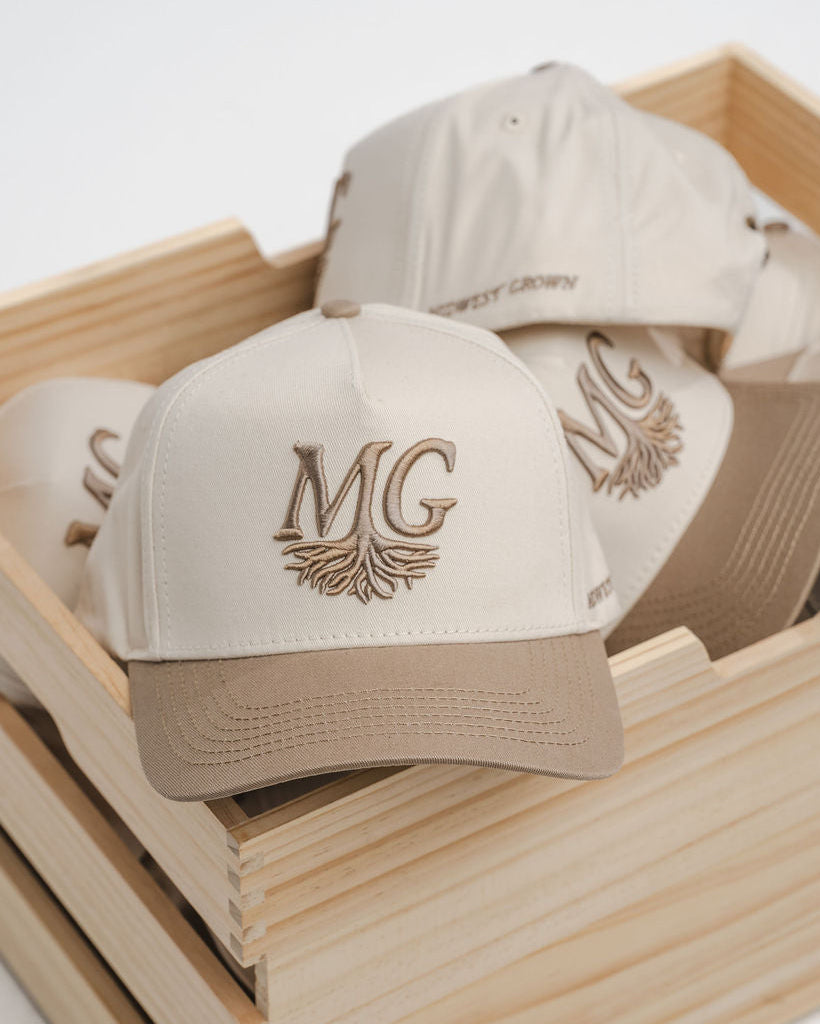 Beige caps with 'Midwest Grown' logo in a wooden box on a white background