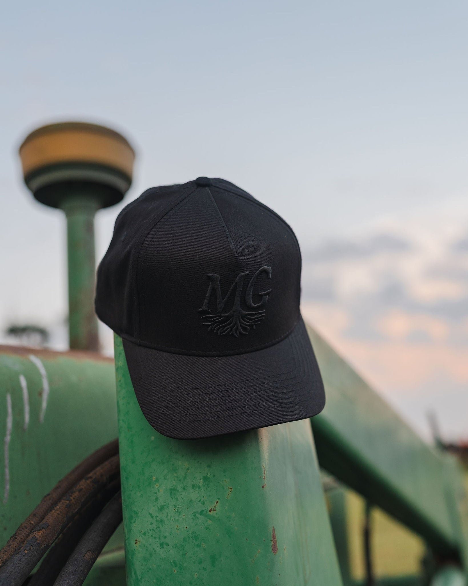 Black cap with 'Midwest Grown' logo on a green tractor against a sky background