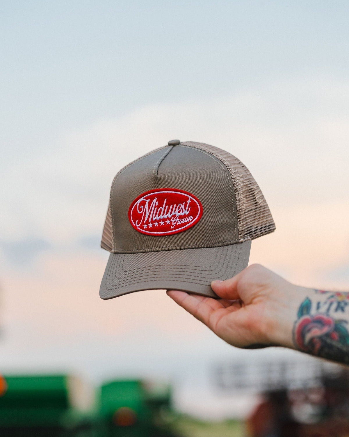 Hand holding the khaki Heartland Trucker outdoors