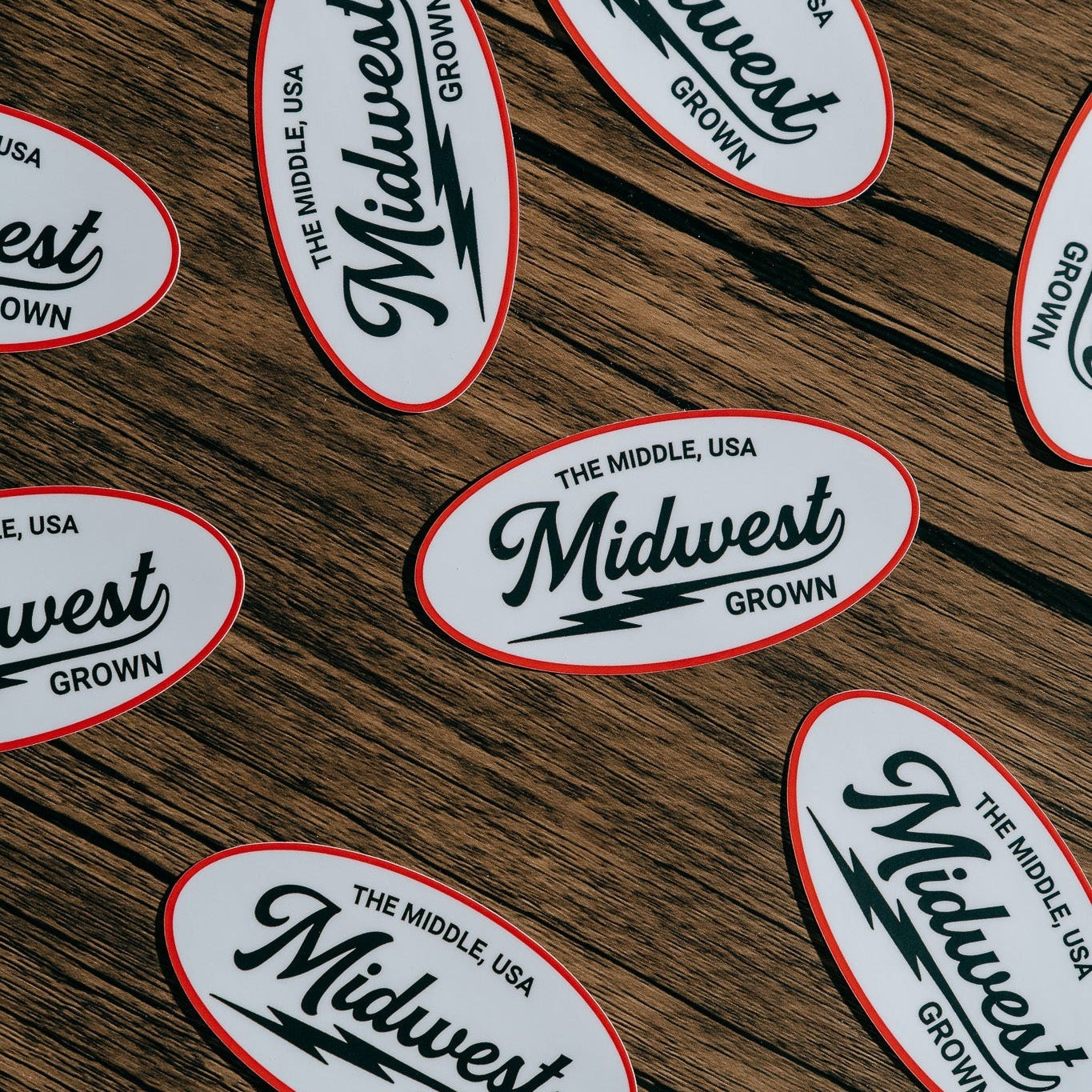 Multiple 'Midwest Grown' stickers on a wooden surface