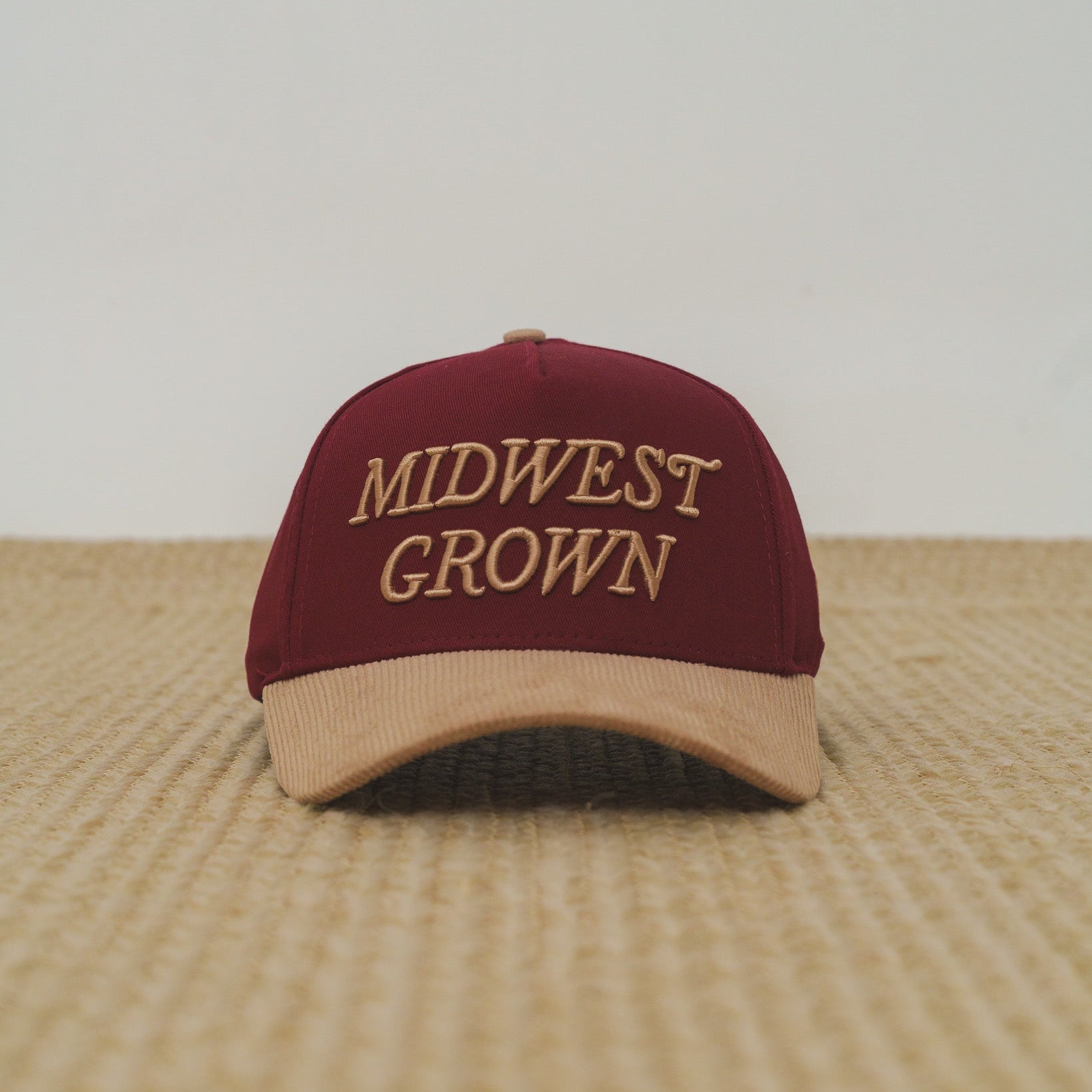 Maroon and beige cap with 'Midwest Grown' text on a textured surface.