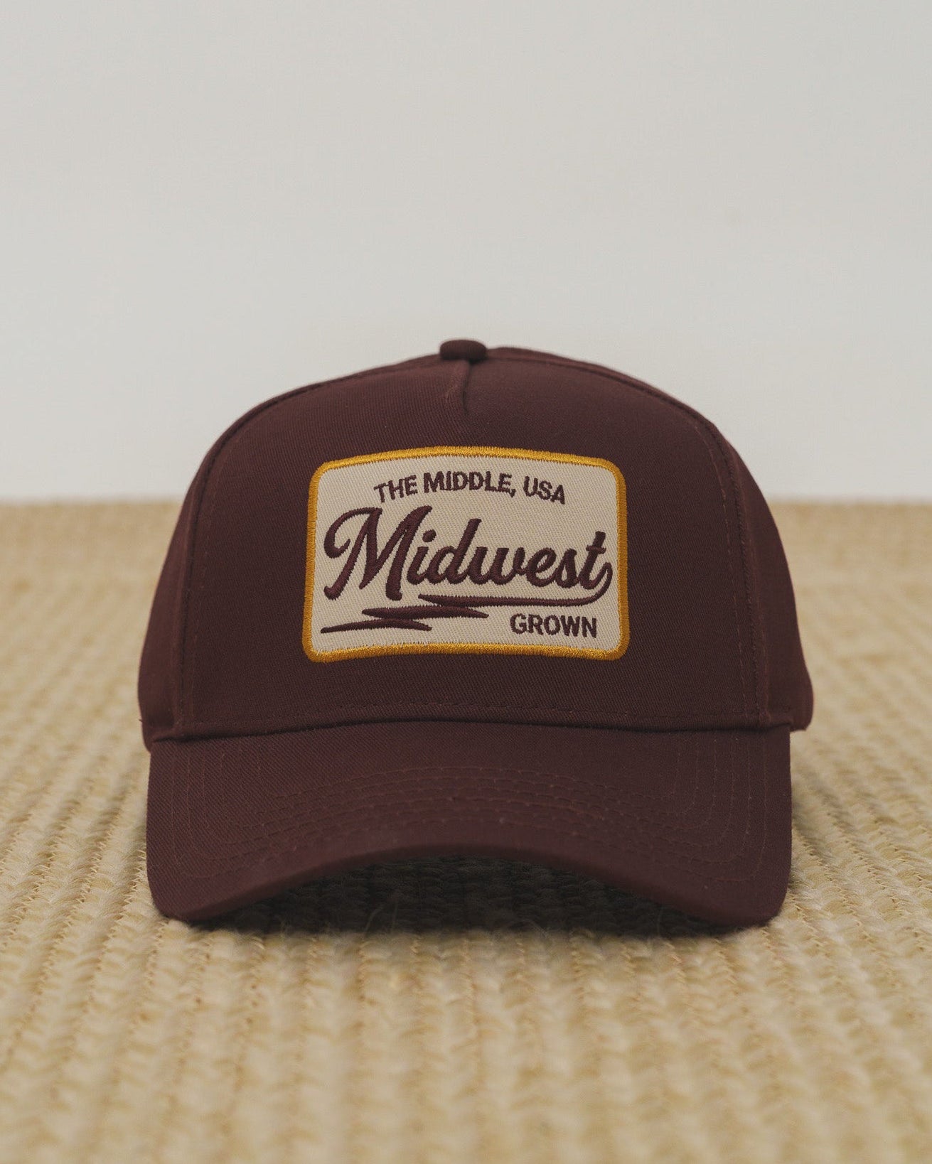 Brown cap with 'Midwest Grown' logo on a textured surface