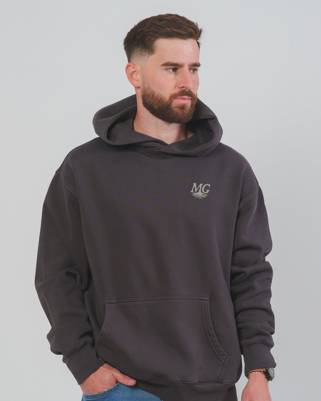 Man wearing a dark gray Midwest Grown hoodie with a logo on a light gray background