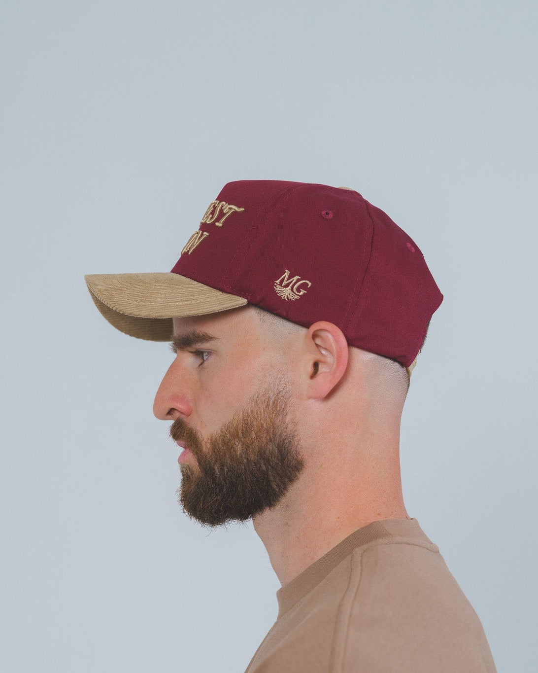 Man wearing a maroon cap with a Midwest Grown logo on a light gray background