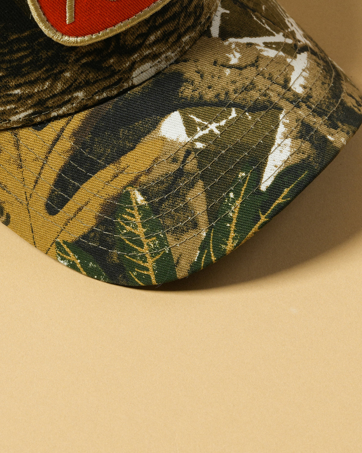 Close-up of the Back Forty Camo Hat’s cotton twill brim, showing the tree-and-branch camouflage print and stitching.
