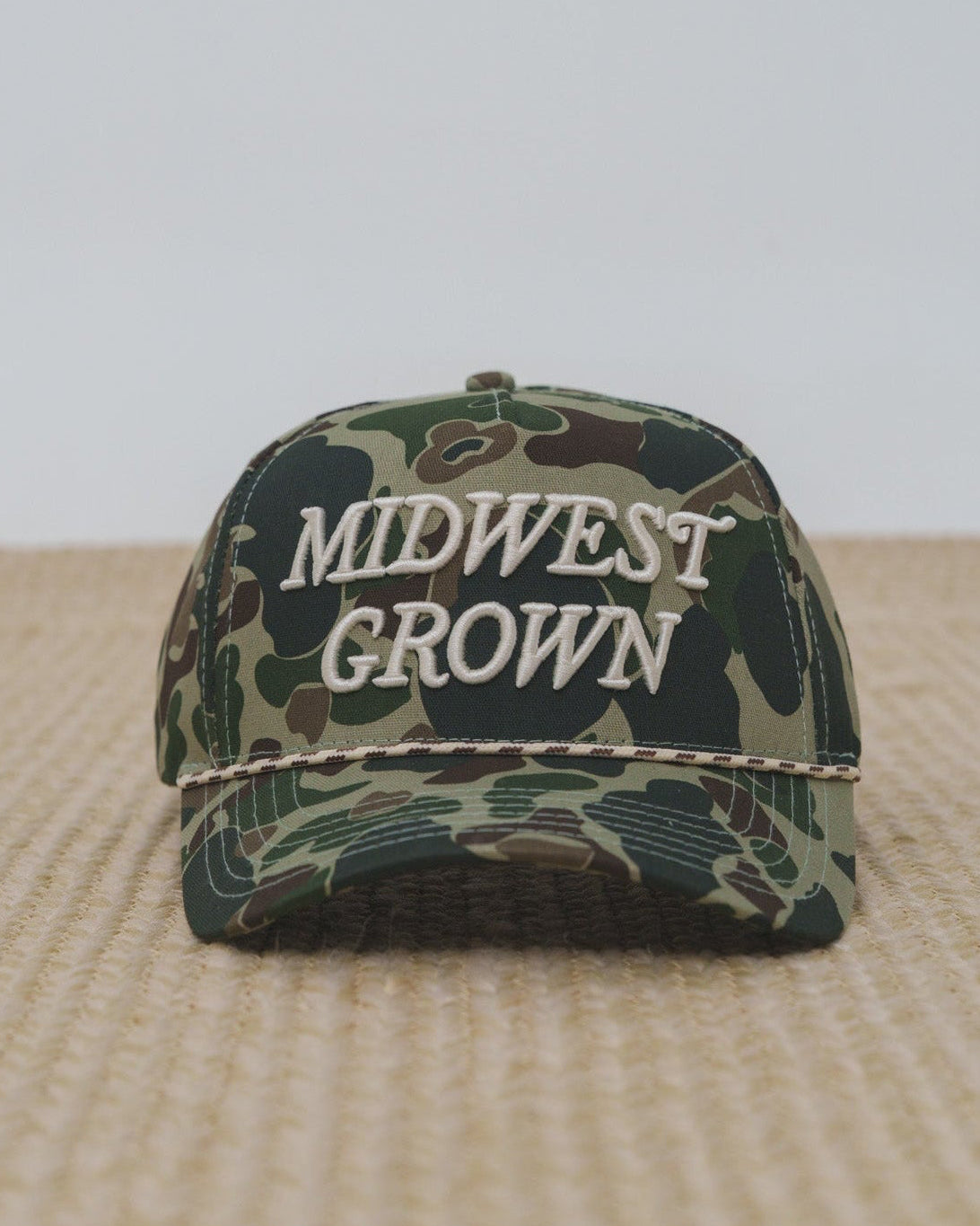 Duck Camouflage cap with 'Midwest Grown' text on a beige surface