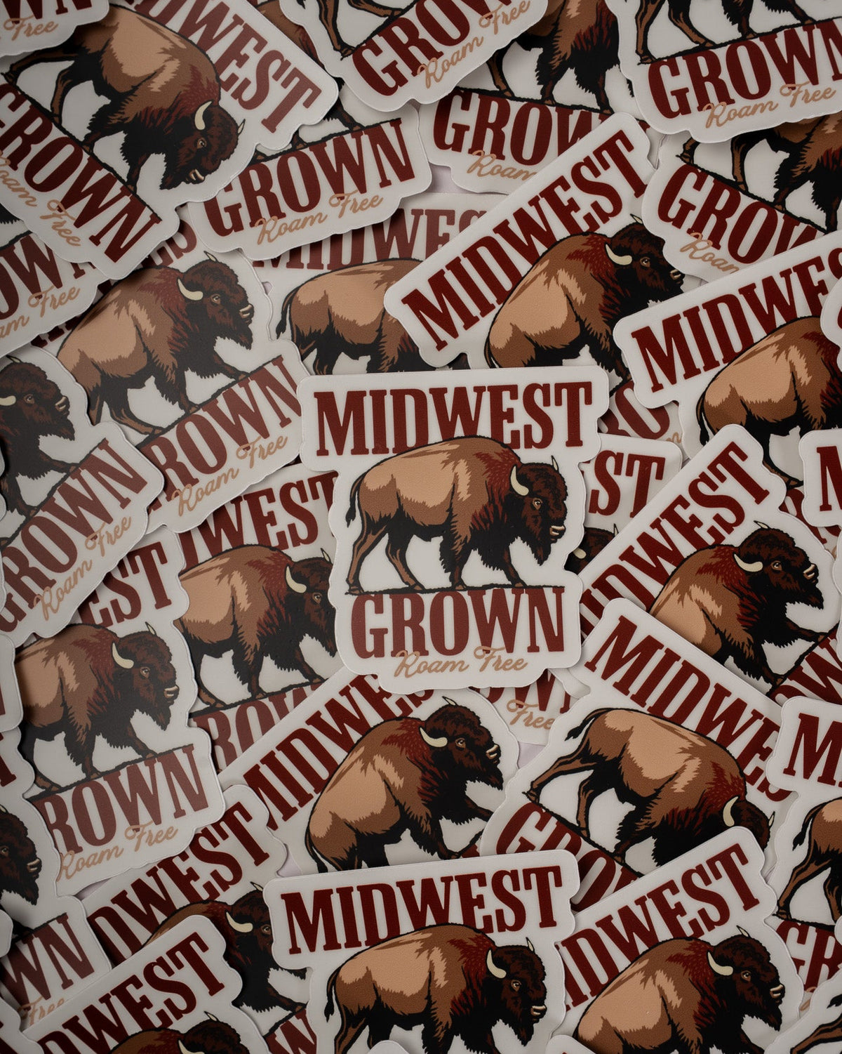 A dense arrangement of die-cut stickers featuring brown bison illustrations and the words 'MIDWEST GROWN in dark red lettering on a white background.