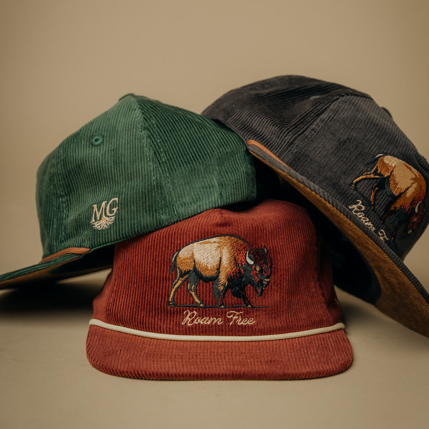 Three Midwest Grown caps with Bison designs on a beige background